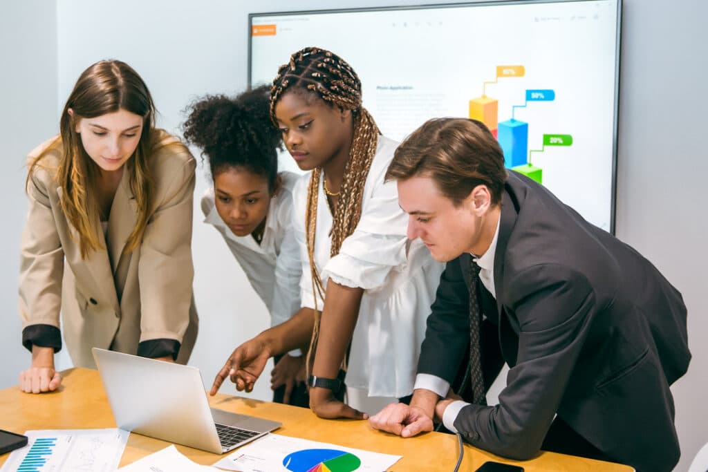 Coworkers gather around a computer in an office to discuss their IT strategy.