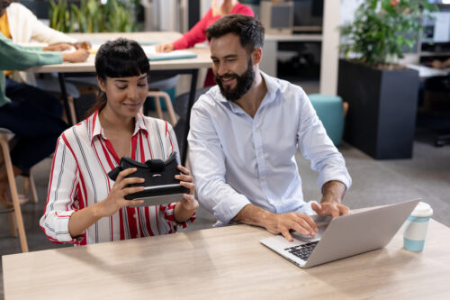 Two people sit at a table and use technology for their small business. They could be using IT services for small businesses